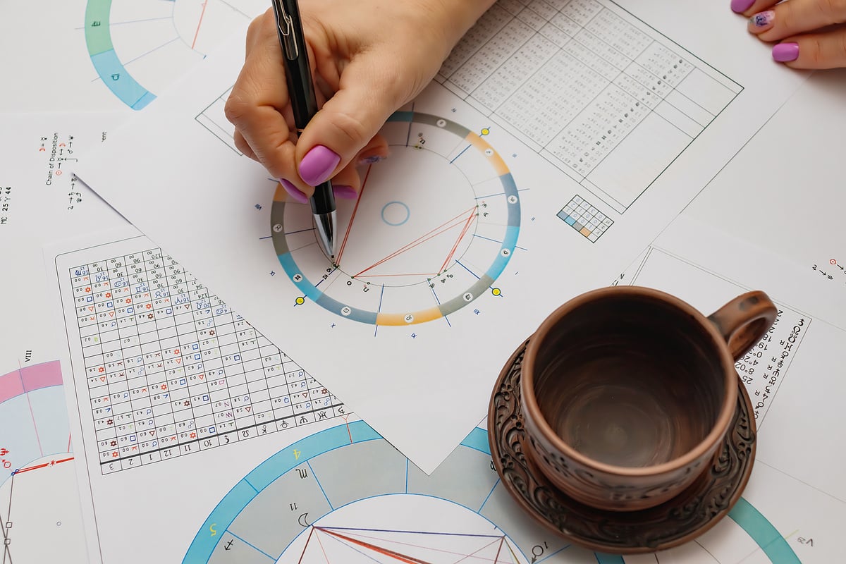 Workplace of a modern astrologer. Printouts of astrological charts, charts, tables, diagrams lying on the table.